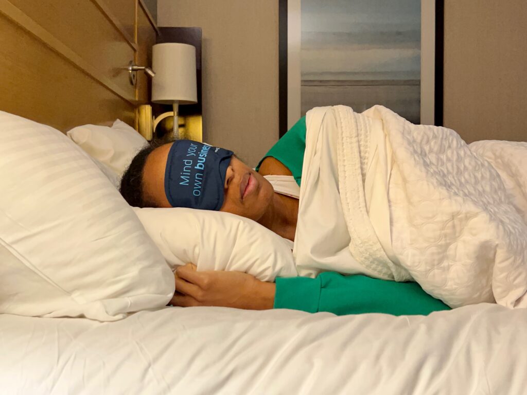 Woman sleeping on side in bed with an eye mask